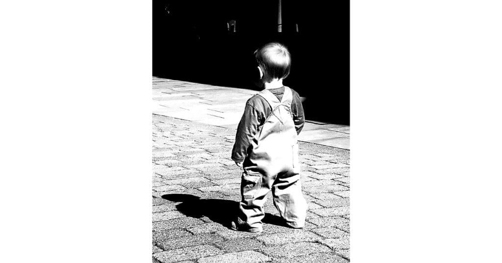 child in overalls standing