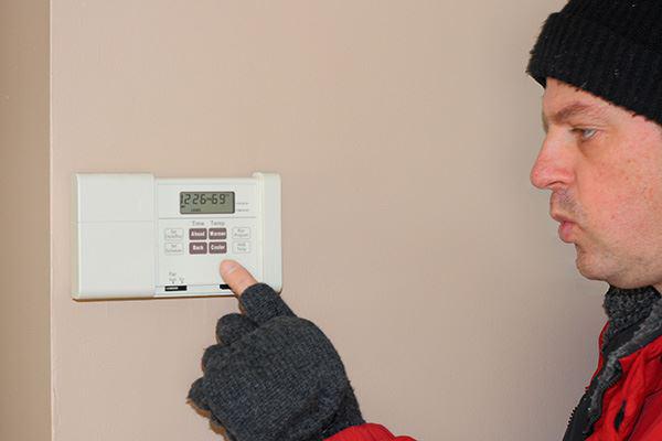 man adjusting thermostat 