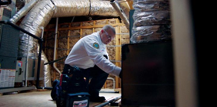 Technician working on HVAC system in attic