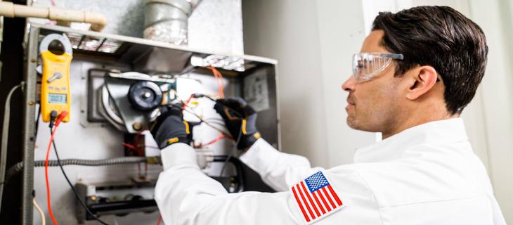 Technician repairing HVAC unit, wearing safety gear