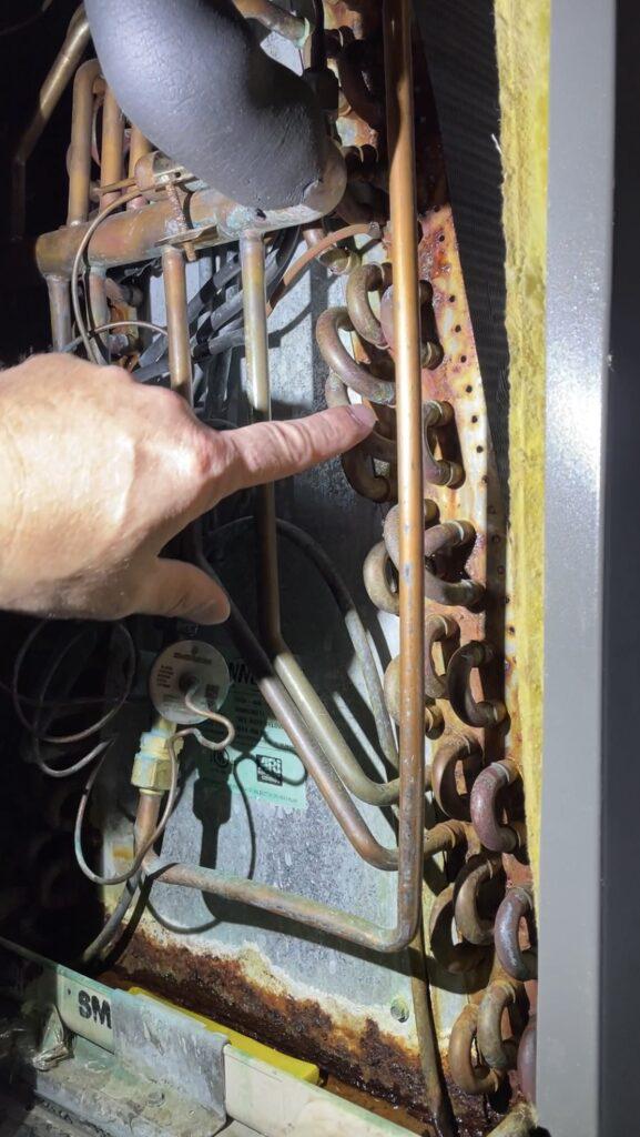 hand pointing to evaporator coil