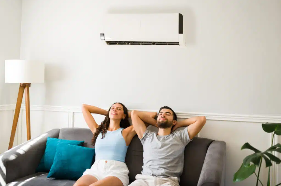 two people relaxing on couch cooling off with ac unit