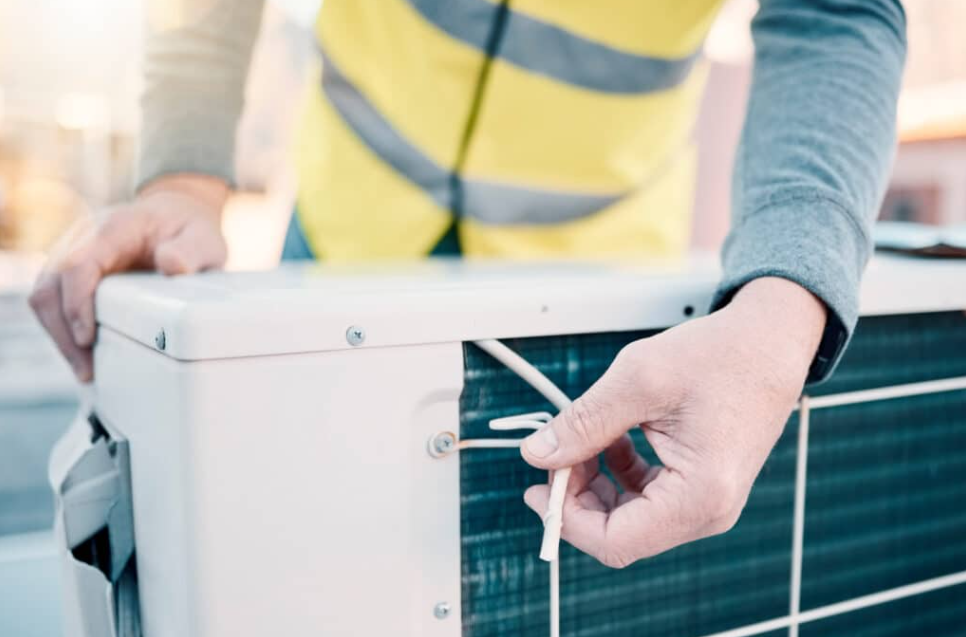 worker adjusting screw on AC unit