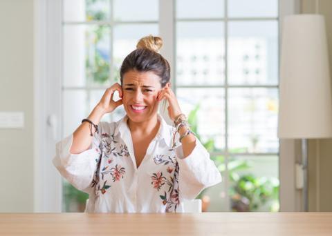 Woman At Home Plugging Ears